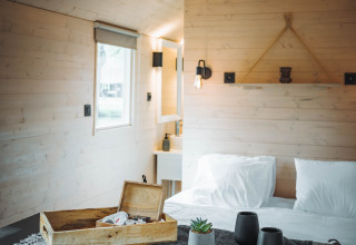 Interior acogedor de la cabaña Gipsy wagon con cama y decoración en Camping Papillon, Bélgica.