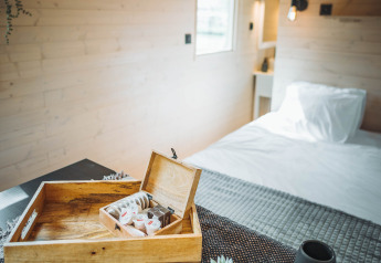 Knus interieur van de Gipsy wagon met houten muren, dienblad, plantje en bed op de achtergrond.