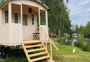 Carro zingaro con terrazza al Camping Papillon in Belgio, situato vicino a uno stagno e alberi.