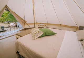 Interno della tenda Bell all’Agriturismo Angeli Sognanti in Italia, con letto accogliente e cuscini colorati.