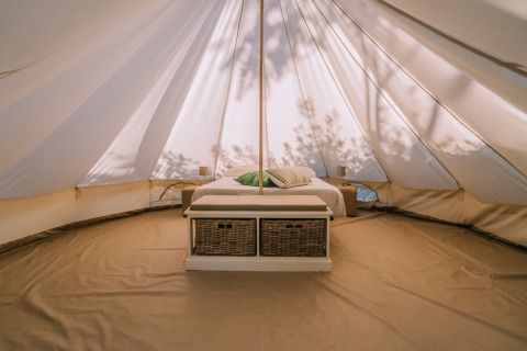 Intérieur de la tente Bell à l’Agriturismo Angeli Sognanti en Italie, avec lit et paniers dessous.