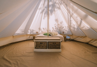 Intérieur de la tente Bell à l’Agriturismo Angeli Sognanti en Italie, avec lit et paniers dessous.