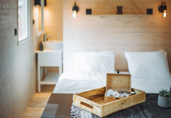 Gemütliches Interieur der Pipowagen-Hütte auf Camping Papillon in Belgien mit Holzwänden und Doppelbett.