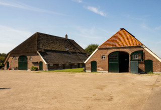 Twee traditionele schuren met rieten en pannendak bij Feather Down Het Wesselink in Salland, Nederland.