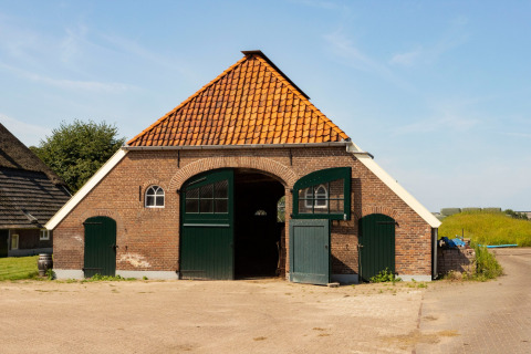 Granero tradicional con tejado rojo y puertas verdes en Feather Down Het Wesselink en Salland, Overijssel.