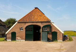 En traditionel ladebygning med rødt tegltag og grønne døre i Feather Down Het Wesselink i Salland, Overijssel.