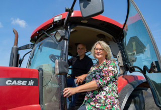 Due persone accanto a un trattore rosso CASE IH sotto il sole a Feather Down Het Wesselink a Salland, Overijssel.