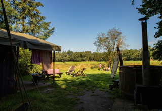 Zicht op een kampeerplaats met ligstoelen en grasveld bij Feather Down Het Wesselink in Salland, Overijssel.