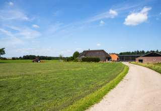 Veduta di Feather Down Het Wesselink a Salland, Overijssel, Paesi Bassi, con fattoria e trattore nel campo.