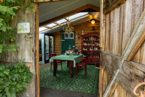 Entrada a un comedor acogedor con paredes de madera y decoración verde en Feather Down Het Wesselink.