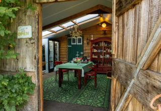 Toegang tot een warme eetkamer met houten muren en groene inrichting bij Feather Down Het Wesselink.
