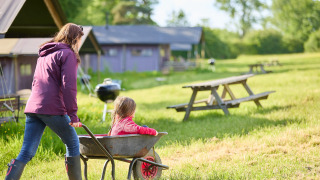 En mor skubber et barn i en trillebør på Feather Down Hidcote Manor Farm, en feriepark i West Midlands.