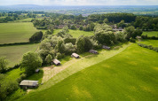 Luftfoto af Feather Down Hidcote Manor Farm i West Midlands, England, omgivet af grønne marker og skove.