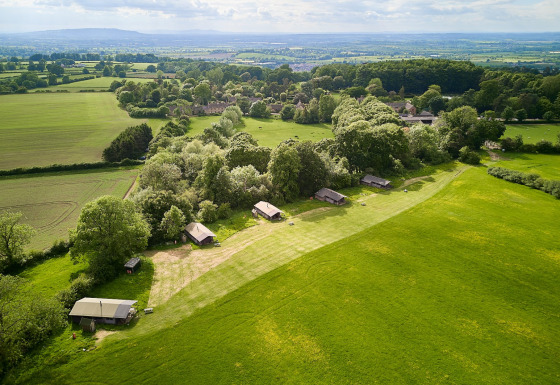 Vista aérea de Feather Down Hidcote Manor Farm en West Midlands, Reino Unido, rodeada de campos verdes y árboles.