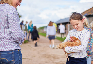 Meisje houdt een kip vast op Feather Down Mount Pleasant, een vakantiepark in Zuidwest-Engeland, Verenigd Koninkrijk.