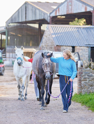 Vrouw begeleidt twee paarden op Feather Down Mount Pleasant, een vakantiepark in Zuidwest-Engeland, VK.