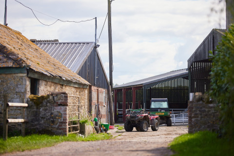 Farmyard buildings and vehicles at Feather Down Mount Pleasant holiday park in South West England, UK.