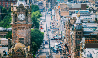 Udsigt over en travl bygade med ikonisk klokketårn og historisk arkitektur i Skotland, Storbritannien.