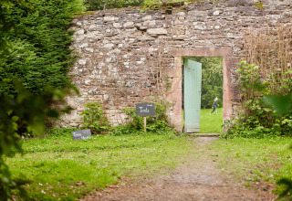 Steinmauer mit offener Tür im Ferienpark Feather Down Chesters, Nordwestengland, Großbritannien.