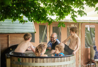 Familie entspannt im Jacuzzi unter Bäumen im Feather Down Chesters Ferienpark, Nordwestengland.