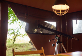 Un telescopio all'interno di una tenda con vista sugli alberi, scattata a Feather Down Chesters nel Regno Unito.