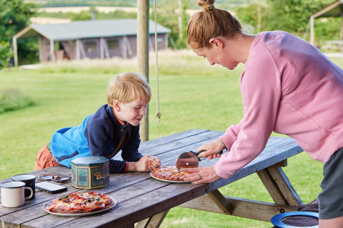 Una mujer corta pizza para un niño en una mesa de picnic en Feather Down East Shilvinghampton, suroeste de Inglaterra.