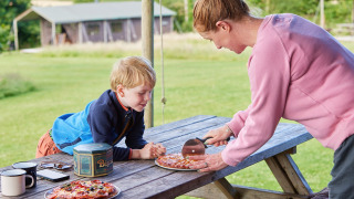 Une femme découpe de la pizza pour un enfant sur une table de pique-nique à Feather Down East Shilvinghampton.