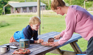 Une femme découpe de la pizza pour un enfant sur une table de pique-nique à Feather Down East Shilvinghampton.