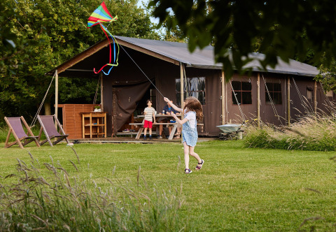 Children fly a kite by a large tent at Feather Down East Shilvinghampton holiday park in South West England.