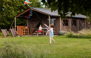 Kinder spielen mit einem Drachen vor einem großen Zelt im Feather Down East Shilvinghampton Ferienpark.