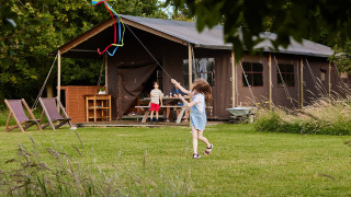 Children fly a kite by a large tent at Feather Down East Shilvinghampton holiday park in South West England.