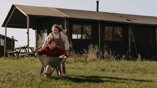 Dos niños juegan con una carretilla delante de una tienda safari en Feather Down Hoeve den Overdraght en Bélgica.