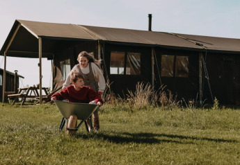Due bambini giocano con una carriola davanti a una tenda safari a Feather Down Hoeve den Overdraght in Belgio.