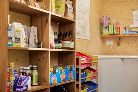 Boerderijwinkel op Feather Down Heydon Grove Farm met houten rekken vol lokale producten en snacks.