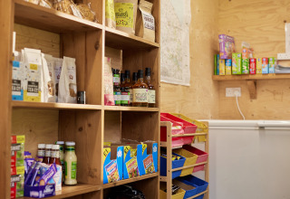 Pequeña tienda del Feather Down Heydon Grove Farm con estantes de madera y productos locales variados.