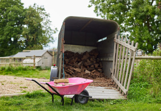Lyserød trillebør foran en trailer fyldt med brænde på Feather Down Heydon Grove Farm i England.