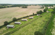 Luftfoto af Feather Down Heydon Grove Farm feriepark, landlige hytter og marker i det østlige England.