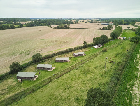 Luftaufnahme des Feather Down Heydon Grove Farm Ferienparks mit Hütten und Feldern in Ostengland.