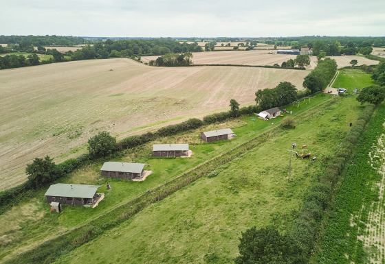 Luftfoto af Feather Down Heydon Grove Farm feriepark, landlige hytter og marker i det østlige England.