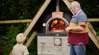 Un adulte et un enfant près d’un four à bois sur Feather Down Heydon Grove Farm, Angleterre de l’Est.