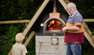 Un adulte et un enfant près d’un four à bois sur Feather Down Heydon Grove Farm, Angleterre de l’Est.