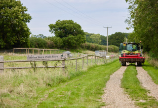 Tractor op grindpad bij Feather Down Farm Days op Heydon Grove Farm, vakantiepark in Oost-Engeland.