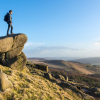 Homme debout sur un grand rocher surplombant le paysage près de Heydon, Est de l'Angleterre, par temps ensoleillé.