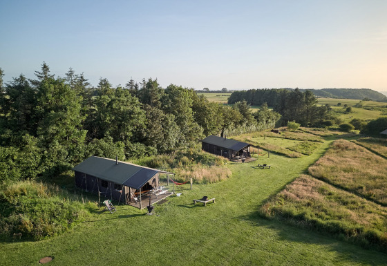 Twee tenten en groene velden bij Feather Down Warren Farm, een vakantiepark in Zuidwest-Engeland, VK.