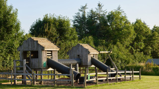 Área de juegos de madera con tubos y cabañas en Feather Down Warren Farm, suroeste de Inglaterra.