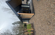 Moderne tiny house Tiny Loft ved Veluwepark de Bosgraaf i Holland med træterrasse og grusstier.