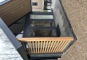 Udendørs område ved Tiny Loft i Veluwepark de Bosgraaf, Holland, med moderne arkitektur og terrasse.