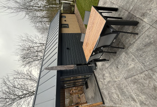 Zona pranzo esterna al Tiny Loft, Veluwepark de Bosgraaf, Paesi Bassi, con arredi moderni e piastrelle.