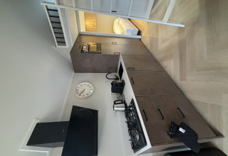 Cucina moderna e compatta nel Tiny Loft di Veluwepark de Bosgraaf, Paesi Bassi, con letto e scala.