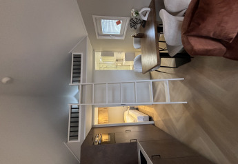 Indvendig udsigt over et tiny house i Veluwepark de Bosgraaf med hems, spisebord og kompakt køkken.